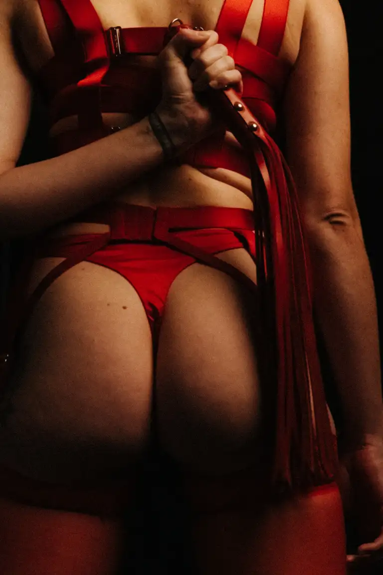 Artistic lingerie photograph showing red strappy lingerie details and accessories, captured in moody light for a South East Queensland modelling portfolio and creative editorial campaign.