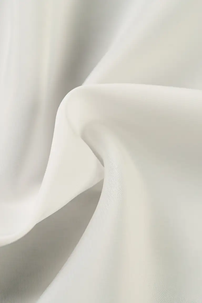 Macro photo of white crepe de chine fabric showing smooth drape and subtle surface texture, photographed in Australia for luxury fabric and eCommerce product detail.