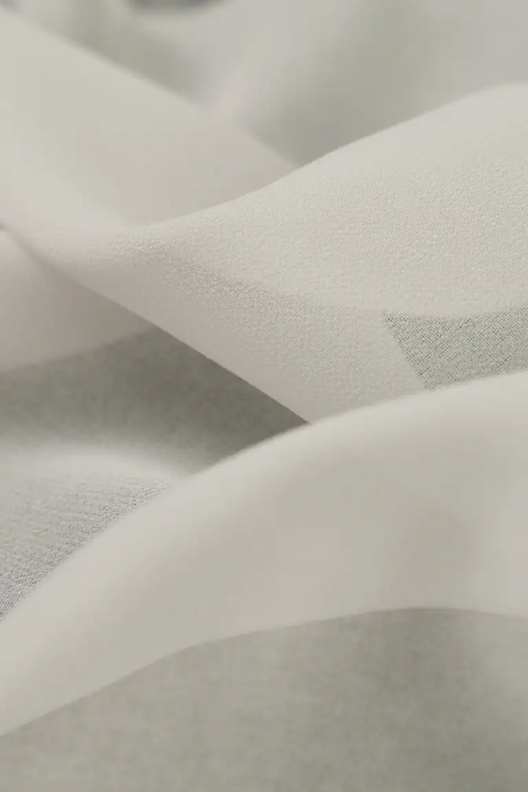 High-end product photography of white georgette fabric, captured in South East Queensland to highlight the sheer texture and flowing weave for textile presentation.