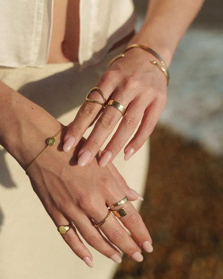 Close-up of gold rings and bracelets styled in a relaxed beachside setting, captured in South East Queensland with a soft, warm boho tone for an eCommerce jewellery brand.
